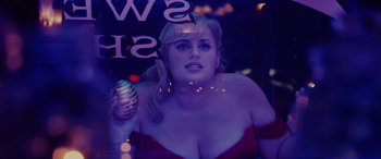Movie still from “Isn't It Romantic” (2019), directed by Todd Strauss-Schulson – A woman in a red dress is holding a microphone; Close Up shot, Over the shoulder angle