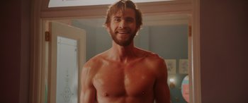 Movie still from “Isn't It Romantic” (2019), directed by Todd Strauss-Schulson – A shirtless man in a room with a mirror; Medium shot, Over the shoulder angle