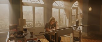 Movie still from “Isn't It Romantic” (2019), directed by Todd Strauss-Schulson – A woman sitting in front of an easel in front of a window; Wide shot, Low angle