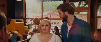 Movie still from “Isn't It Romantic” (2019), directed by Todd Strauss-Schulson – A man and a woman standing next to each other in a restaurant; Medium shot, Over the shoulder angle