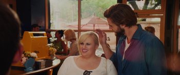 Movie still from “Isn't It Romantic” (2019), directed by Todd Strauss-Schulson – A woman sitting next to a man in front of a window; Medium shot, Over the shoulder angle