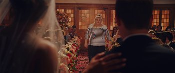Movie still from “Isn't It Romantic” (2019), directed by Todd Strauss-Schulson – A woman walking down the aisle of a wedding ceremony; Wide shot, Over the shoulder angle