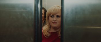 Movie still from “Isn't It Romantic” (2019), directed by Todd Strauss-Schulson – A woman with blonde hair and a red shirt is in an elevator; Close Up shot, Over the shoulder angle