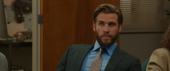 Movie still from “Isn't It Romantic” (2019), directed by Todd Strauss-Schulson – A man in a suit and tie looking to his left; Close Up shot, Over the shoulder angle