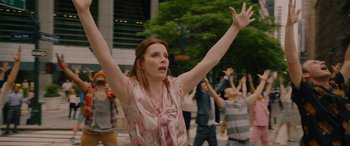 Movie still from “Isn't It Romantic” (2019), directed by Todd Strauss-Schulson – A woman in a pink shirt is holding her hands up; Medium shot, Low angle
