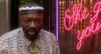 Movie still from “It Could Happen to You” (1994), directed by Andrew Bergman – A man with a beard wearing a hat and a tie; Close Up shot, Low angle