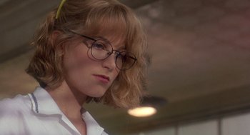 Movie still from “It Could Happen to You” (1994), directed by Andrew Bergman – A person wearing glasses and a white shirt; Close Up shot, Low angle