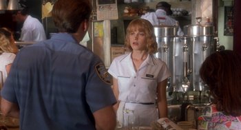 Movie still from “It Could Happen to You” (1994), directed by Andrew Bergman – A woman in a white shirt is talking to a man in a police uniform; Medium shot, Over the shoulder angle