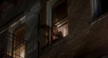 Movie still from “It Could Happen to You” (1994), directed by Andrew Bergman – A woman looking out of a window at night; Wide shot, Low angle