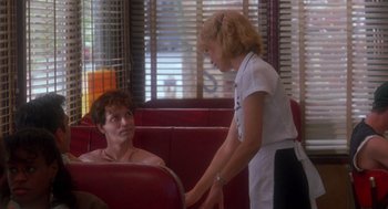 Movie still from “It Could Happen to You” (1994), directed by Andrew Bergman – Two people sitting in a booth talking to each other; Medium shot, Over the shoulder angle