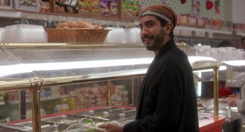 Movie still from “It Could Happen to You” (1994), directed by Andrew Bergman – A man standing in front of a display case; Medium shot, Over the shoulder angle
