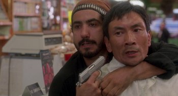 Movie still from “It Could Happen to You” (1994), directed by Andrew Bergman – A man holding a gun in front of another man in a store; Close Up shot, Low angle