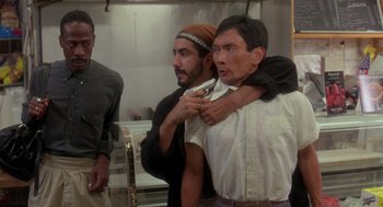 Movie still from “It Could Happen to You” (1994), directed by Andrew Bergman – A group of men standing next to each other in a room; Medium shot, Over the shoulder angle
