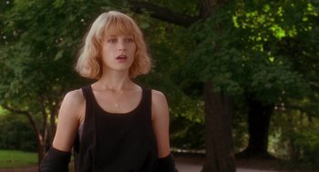Movie still from “It Could Happen to You” (1994), directed by Andrew Bergman – A woman with blonde hair standing in front of a tree; Medium shot, Low angle