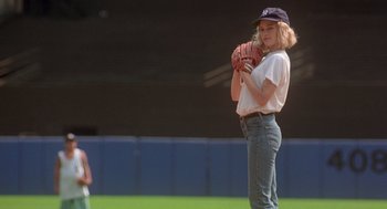 Movie still from “It Could Happen to You” (1994), directed by Andrew Bergman – A woman is holding a baseball glove on a field; Wide shot, Low angle
