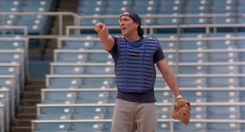 Movie still from “It Could Happen to You” (1994), directed by Andrew Bergman – A baseball player wearing a catcher's gear pointing; Medium shot, Low angle