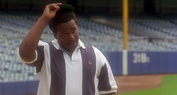 Movie still from “It Could Happen to You” (1994), directed by Andrew Bergman – A baseball player is holding his hat up; Close Up shot, Low angle