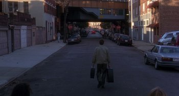 Movie still from “It Could Happen to You” (1994), directed by Andrew Bergman – A man walking down the street holding two suitcases; Wide shot, High angle