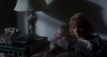 Movie still from “It Could Happen to You” (1994), directed by Andrew Bergman – A woman sitting on a bed in a dark room; Medium shot, Low angle