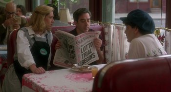 Movie still from “It Could Happen to You” (1994), directed by Andrew Bergman – A man and a woman sitting at a table reading a newspaper; Medium shot, Over the shoulder angle