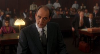Movie still from “It Could Happen to You” (1994), directed by Andrew Bergman – A man wearing a suit and tie in a courtroom; Medium shot, Low angle