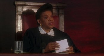 Movie still from “It Could Happen to You” (1994), directed by Andrew Bergman – A woman in a courtroom holding a piece of paper in her hands; Close Up shot, Low angle