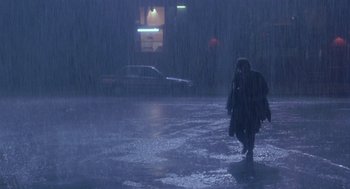 Movie still from “It Could Happen to You” (1994), directed by Andrew Bergman – A person walking in the rain on the sidewalk; Wide shot, High angle