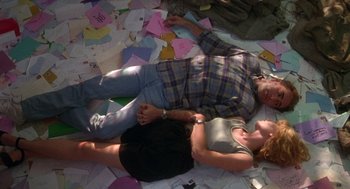 Movie still from “It Could Happen to You” (1994), directed by Andrew Bergman – A man and a woman laying on the ground; Wide shot, Overhead angle