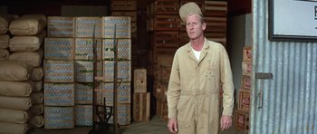 Movie still from “It Happened at the World's Fair” (1963), directed by Norman Taurog – A man wearing a hat standing in a warehouse; Medium shot, Low angle