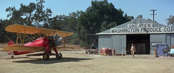 Movie still from “It Happened at the World's Fair” (1963), directed by Norman Taurog – An airplane parked in front of a building; Extreme Wide shot, Low angle