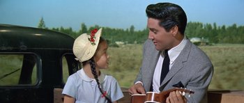 Movie still from “It Happened at the World's Fair” (1963), directed by Norman Taurog – A man and a little girl sitting next to each other; Medium shot, Over the shoulder angle