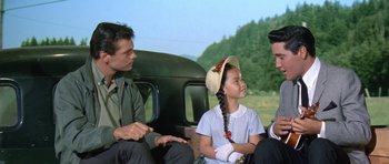 Movie still from “It Happened at the World's Fair” (1963), directed by Norman Taurog – Two men and a little girl sitting on the back of a truck; Medium shot, Over the shoulder angle