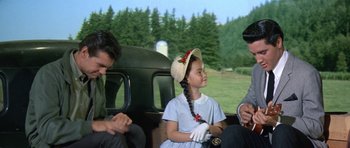 Movie still from “It Happened at the World's Fair” (1963), directed by Norman Taurog – A young girl sitting on the back of a car; Medium shot, Over the shoulder angle