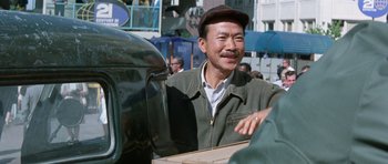 Movie still from “It Happened at the World's Fair” (1963), directed by Norman Taurog – An older man wearing a hat standing next to a car; Close Up shot, Over the shoulder angle