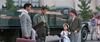 Movie still from “It Happened at the World's Fair” (1963), directed by Norman Taurog – A group of people standing next to each other near a truck; Medium shot, Over the shoulder angle