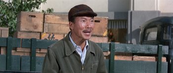 Movie still from “It Happened at the World's Fair” (1963), directed by Norman Taurog – An asian man wearing a hat and a jacket; Close Up shot, Over the shoulder angle