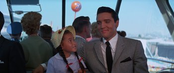 Movie still from “It Happened at the World's Fair” (1963), directed by Norman Taurog – A man and a little girl posing for a picture; Medium shot, Over the shoulder angle