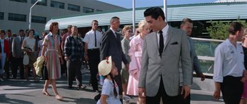 Movie still from “It Happened at the World's Fair” (1963), directed by Norman Taurog – A group of people standing in a line; Medium shot, Over the shoulder angle