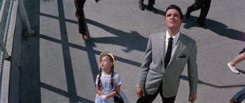 Movie still from “It Happened at the World's Fair” (1963), directed by Norman Taurog – A little girl standing next to a man in a suit; Medium shot, Low angle