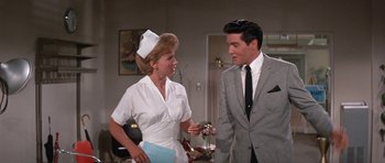 Movie still from “It Happened at the World's Fair” (1963), directed by Norman Taurog – A man and a woman talking in a room; Medium shot, Over the shoulder angle