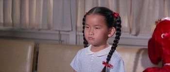 Movie still from “It Happened at the World's Fair” (1963), directed by Norman Taurog – A little girl with pigtails sitting on a couch; Close Up shot, High angle