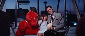 Movie still from “It Happened at the World's Fair” (1963), directed by Norman Taurog – A man and a little girl sitting next to a red dog; Medium shot, High angle