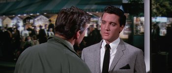 Movie still from “It Happened at the World's Fair” (1963), directed by Norman Taurog – A man wearing a suit and tie talking to another man wearing a jacket; Medium shot, Over the shoulder angle