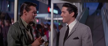 Movie still from “It Happened at the World's Fair” (1963), directed by Norman Taurog – A man in a suit and tie talking to another man in a suit and tie; Medium shot, Over the shoulder angle