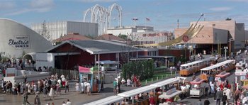 Movie still from “It Happened at the World's Fair” (1963), directed by Norman Taurog – A crowd of people standing on a walkway near an amusement park; Extreme Wide shot, High angle