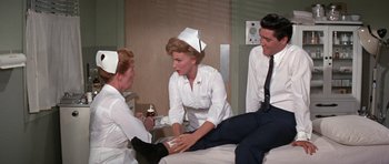 Movie still from “It Happened at the World's Fair” (1963), directed by Norman Taurog – A group of nurses sitting on top of a hospital bed; Medium shot, Low angle
