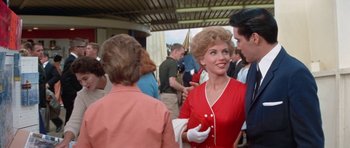Movie still from “It Happened at the World's Fair” (1963), directed by Norman Taurog – A woman in a red dress talking to a man in a red suit; Medium shot, Over the shoulder angle