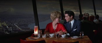 Movie still from “It Happened at the World's Fair” (1963), directed by Norman Taurog – A man and a woman sitting at a dinner table; Medium shot, Over the shoulder angle