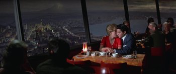 Movie still from “It Happened at the World's Fair” (1963), directed by Norman Taurog – A man and a woman sitting at a table in front of a window; Medium shot, Over the shoulder angle