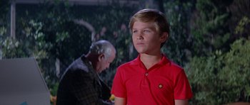 Movie still from “It Happened at the World's Fair” (1963), directed by Norman Taurog – A young boy in a red shirt is looking at the camera; Close Up shot, Over the shoulder angle